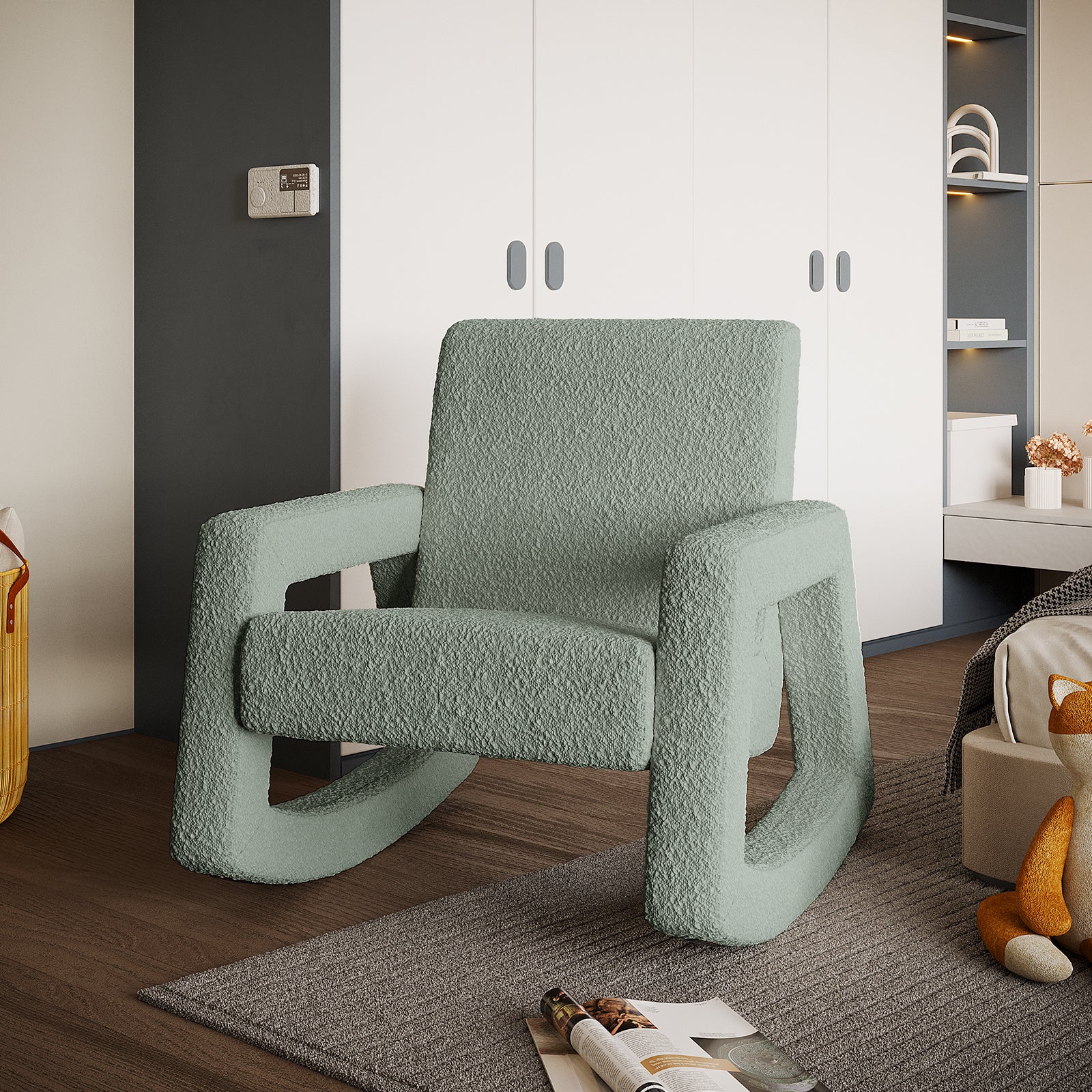 Ligeia Boucle Padded Rocking Chair in Mint Green on dark wood floor with white storage wall and decorative shelf behind, woven basket, open magazine, and plush fox toy nearby.