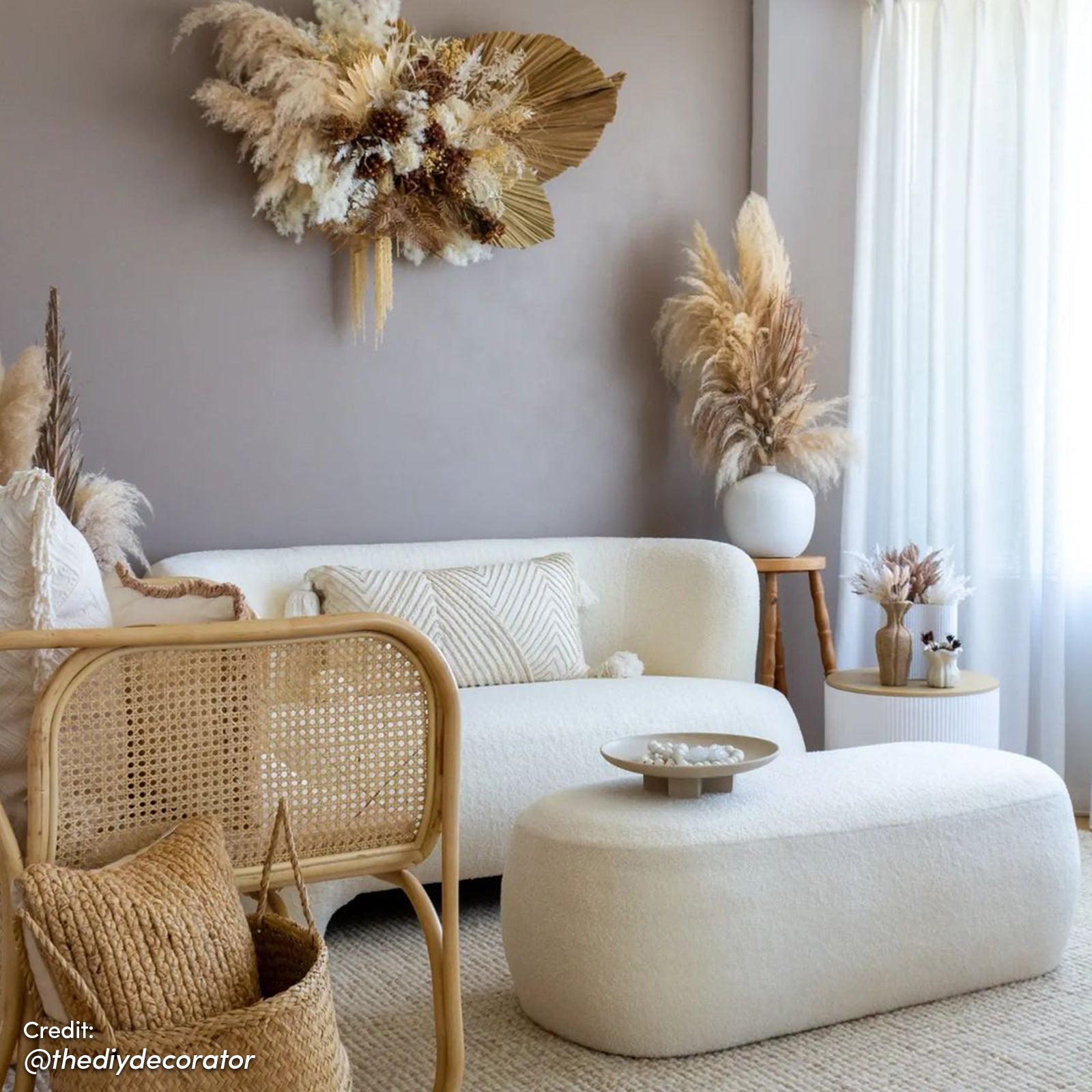 Massie 2 Seater Boucle Sofa in Cream White, featuring a curved design and plush texture, set in a boho-Scandi sitting area with a matching ottoman and rattan accents.