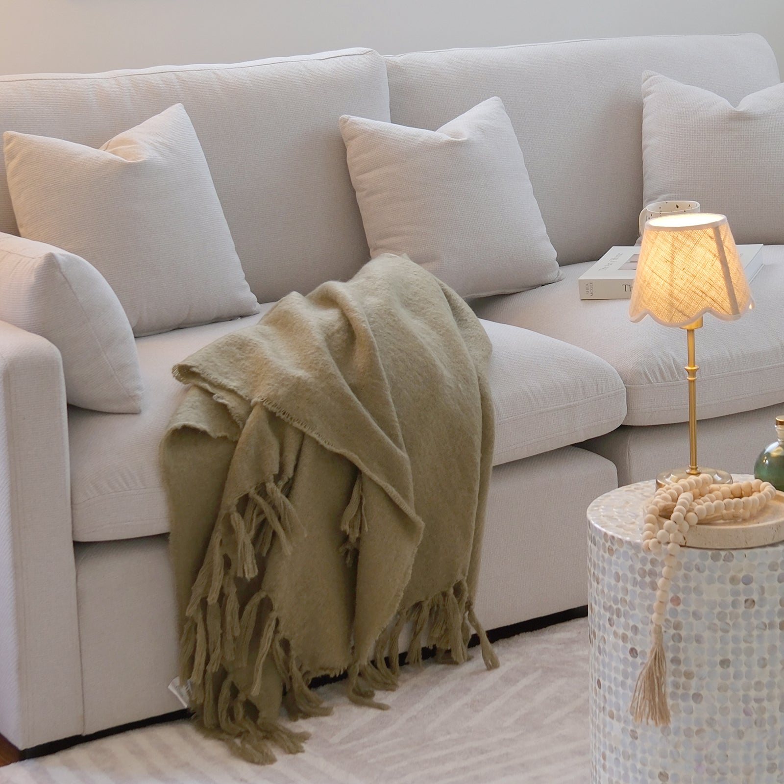 Millie 3-Seater Fabric Modular Sofa in warm light grey on a couch with a blanket and white pillow, showcasing its spacious design and plush cushions for ultimate comfort in any living room setting.