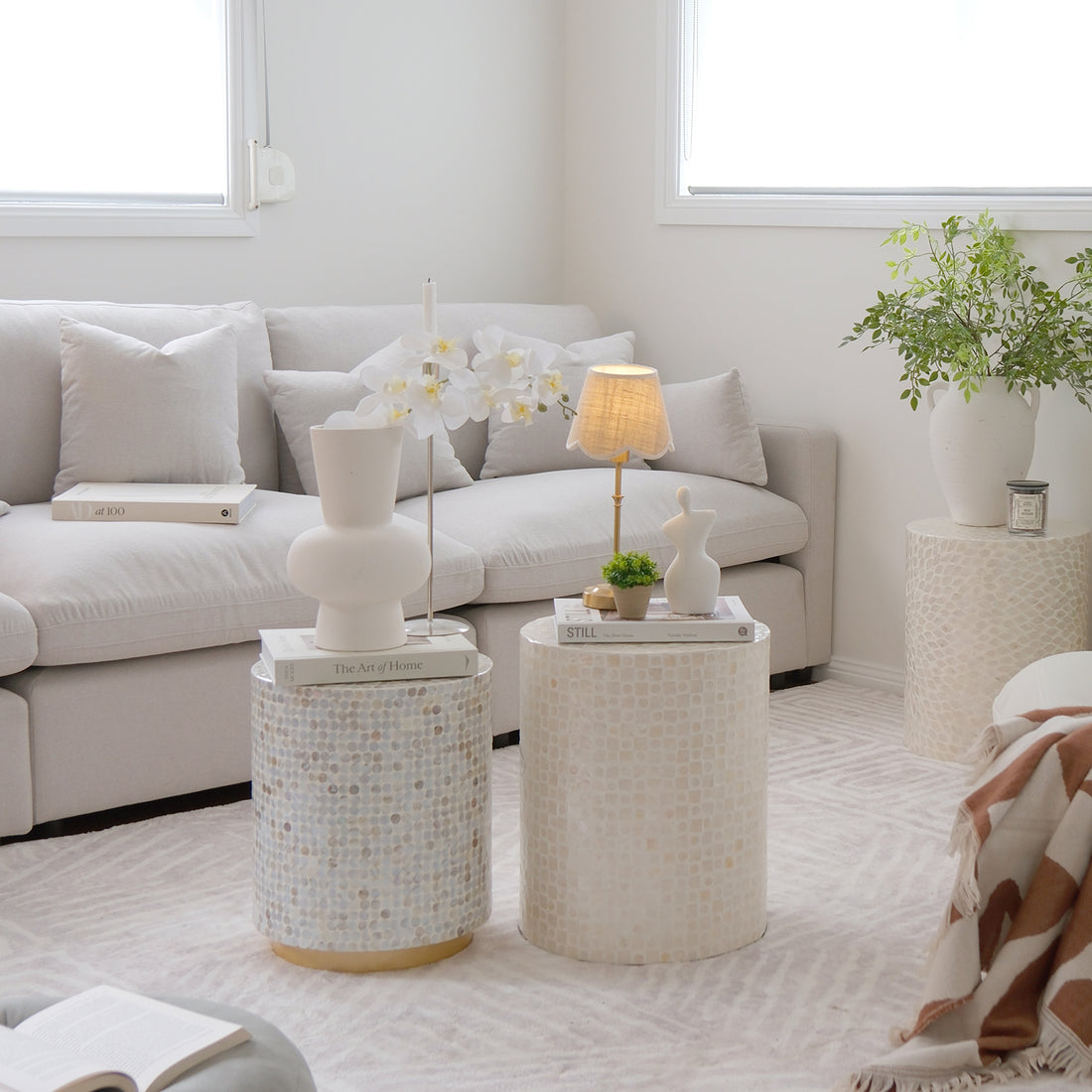 Millie 4-Seater Fabric Modular Sofa in warm light grey, featuring deep plush seats, visible modular sections, and minimalist lines, set in a cozy interior with a lamp, blanket, and potted plant nearby.