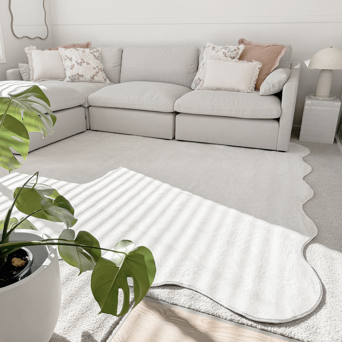 Millie 5 Seater Spill Resistant Fabric Sofa in Warm Light Grey features a low-profile design with plush cushions, surrounded by soft throw pillows, perfect for a cozy, minimalist living space.