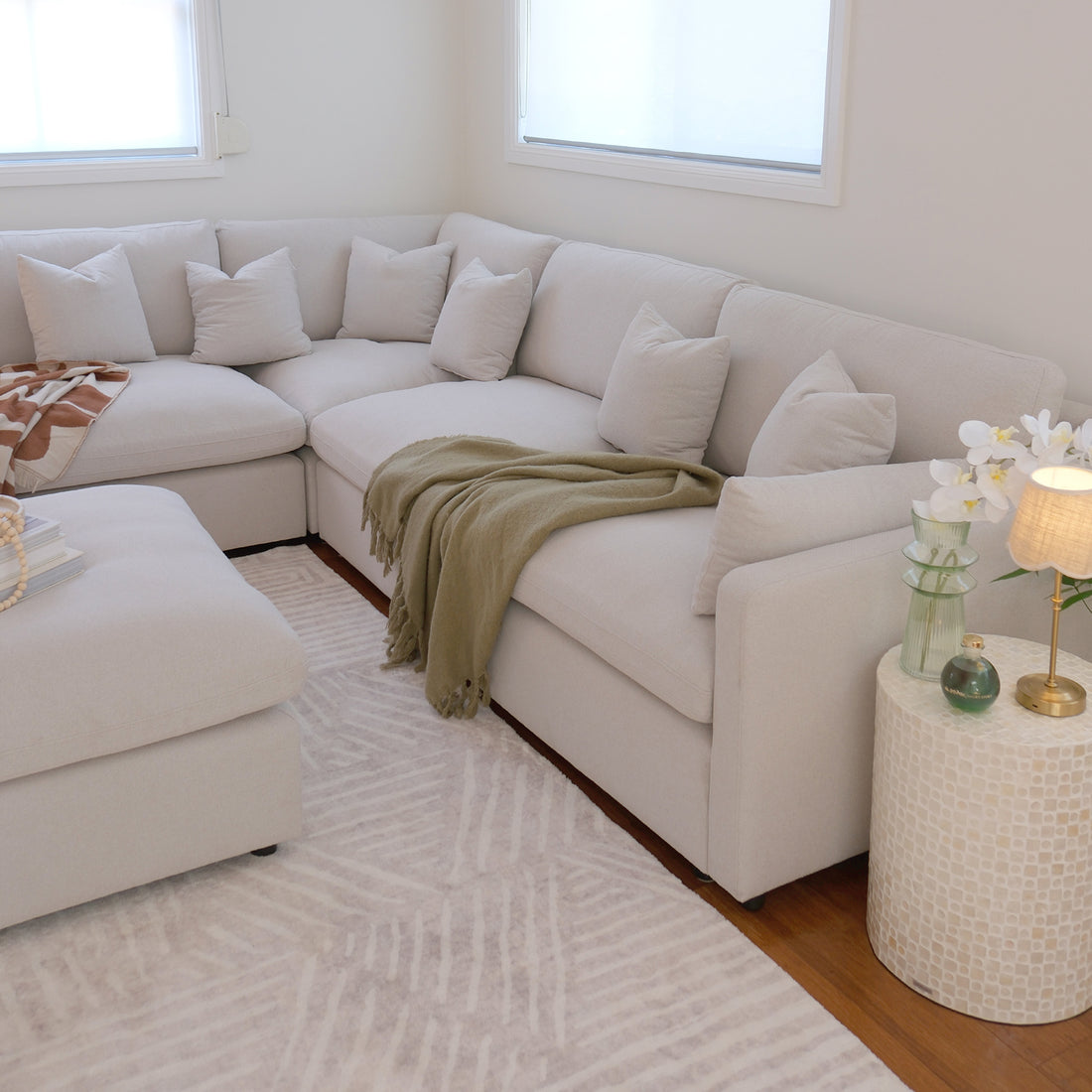 Millie 6-Seater Fabric Corner Chaise Sofa – Warm Light Grey on display, featuring a plush cushion on a couch, highlighting its spacious modular design and comfortable, deep seating.