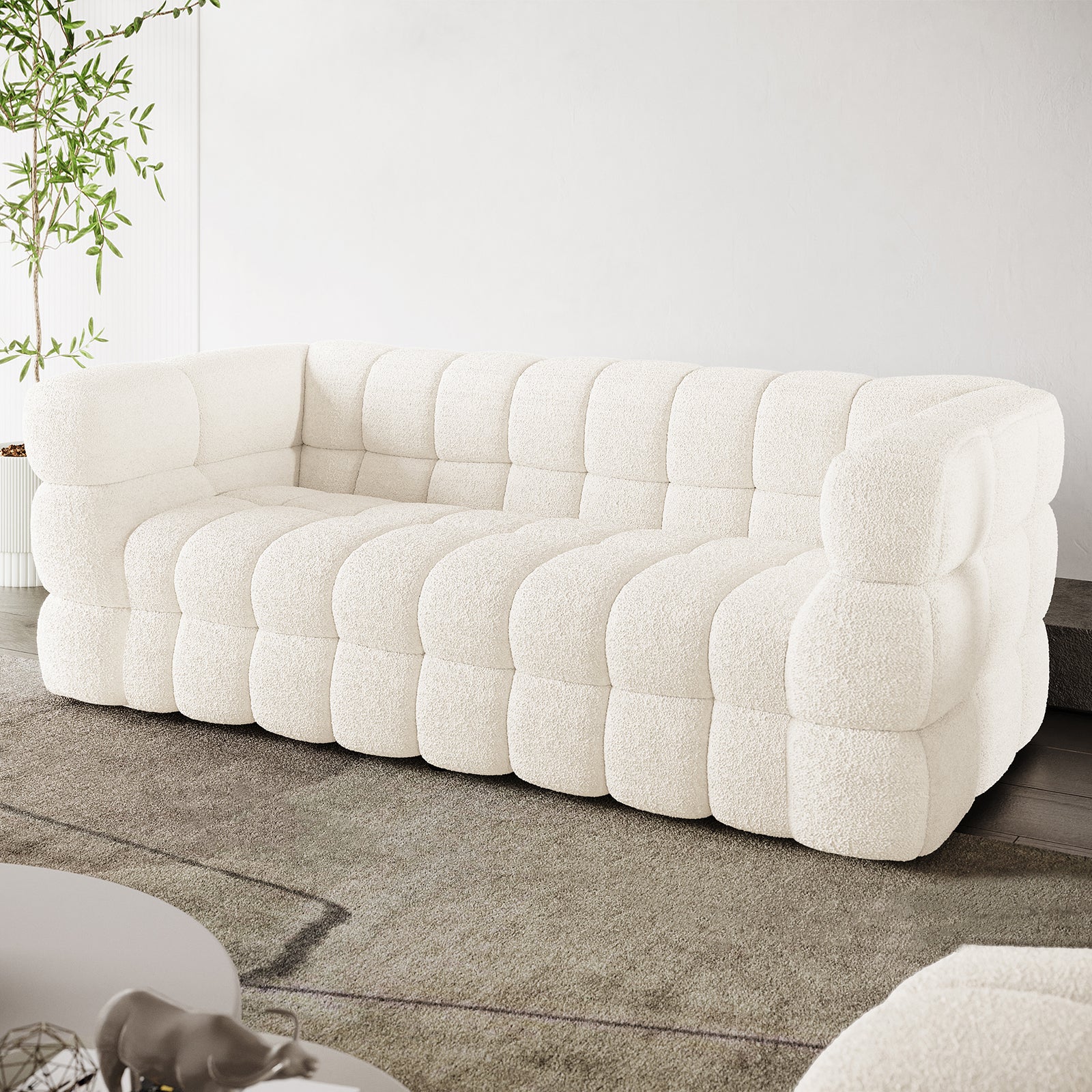Norah 3 Seater Boucle Sofa in Cream White features a modular design with pillowy, tufted blocks, upholstered in off-white bouclé fabric, set in a bright, minimalist living room.
