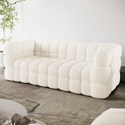 Norah 3 Seater Boucle Sofa in Cream White features a modular design with pillowy, tufted blocks, upholstered in off-white bouclé fabric, set in a bright, minimalist living room.