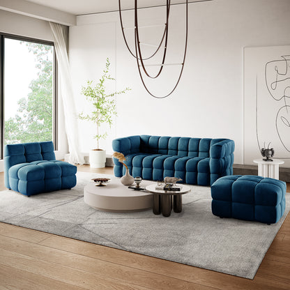 Norah 5 Seater Velvet Sofa Set with Ottoman in Blue, featuring a quilted-block design, modular configuration, and deep tufting, complemented by two ottomans on a light gray rug.