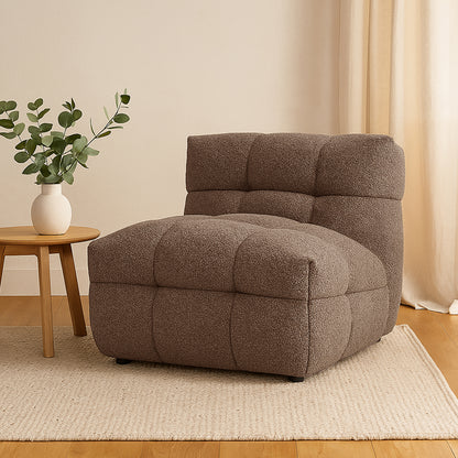 Norah Boucle Single Seater Sofa in Brown, featuring tufted upholstery, sits on a light-beige rug. A small wooden side table with a white vase complements the cozy, modern setup.