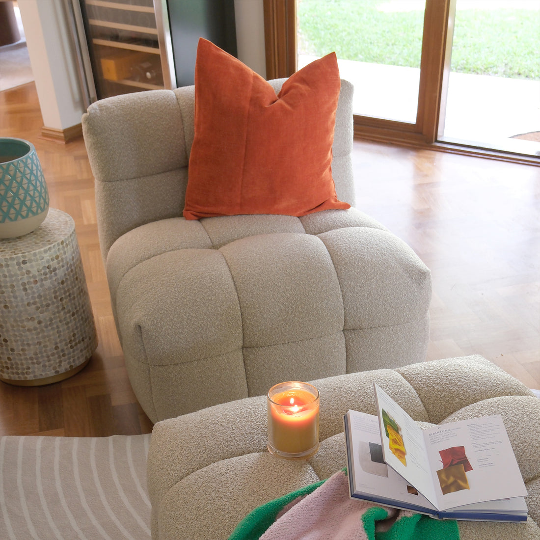 Norah Boucle Single Seater Sofa in Warm Beige, featuring soft bouclé upholstery, deep cushioning, and rust-orange velvet pillow, paired with a tufted ottoman and mosaic side table in a cozy lounge setting.
