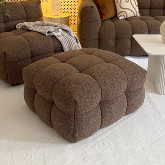 Norah Boucle Ottoman in Brown, a large square tufted piece in cozy bouclé fabric, complements the matching seating area, providing stylish versatility as a footrest or chic coffee table alternative.