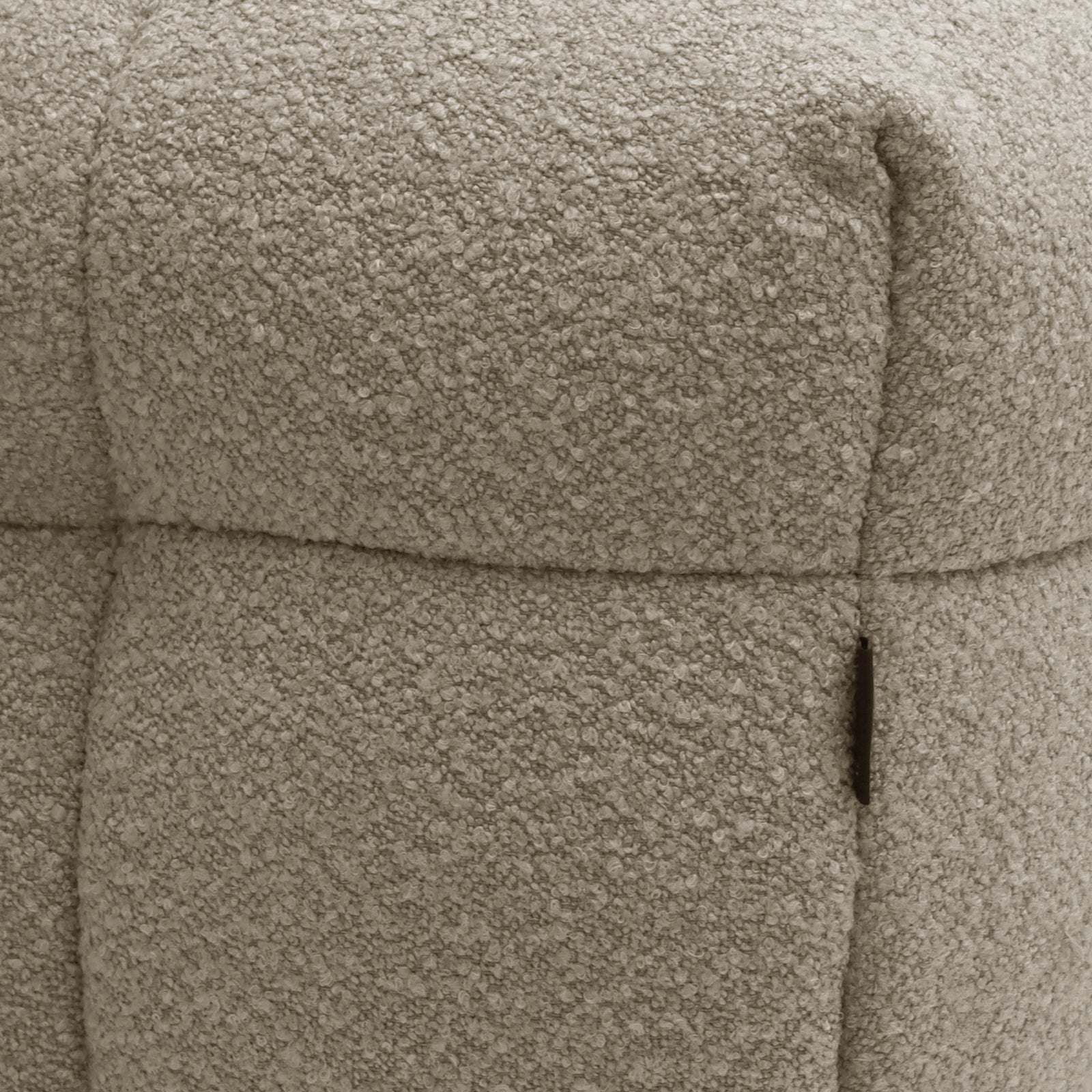 Close-up of the Norah Boucle Ottoman in Warm Beige, highlighting its soft boucle fabric texture around the seam and pocket area, showcasing its plush and sophisticated design.