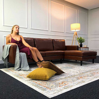 Nornas 3 Seater PU Leather Sofa with Chaise features a sleek design with deep foam cushioning, comfortably seating a woman on a couch with its modular layout, highlighting its practicality and style.