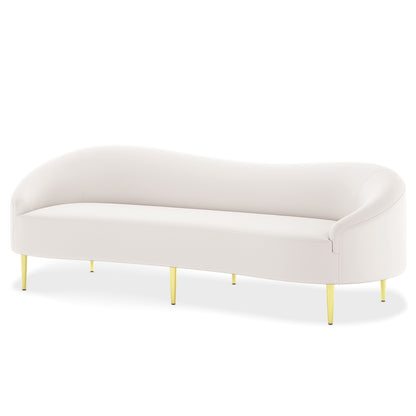 Prima 3 Seater Velvet Sofa in Cream features a modern, curved design with a smooth back and arms, supported by brass-toned, tapered metal legs on a white background.