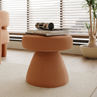 Sadi Velvet Fabric Round Mushroom Ottoman in Burnt Orange, upholstered in terracotta-like material, serves as a stylish centerpiece with art books on top, set against a modern, cozy interior backdrop.