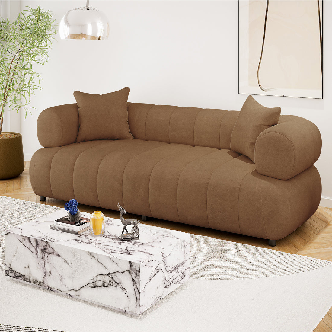Samira 3 Seater Velvet Sofa in Camel Brown, showcasing plush velvet upholstery, three-seater design, and elegant cushioning, set in a stylish room with a brown couch and blue flower vase.