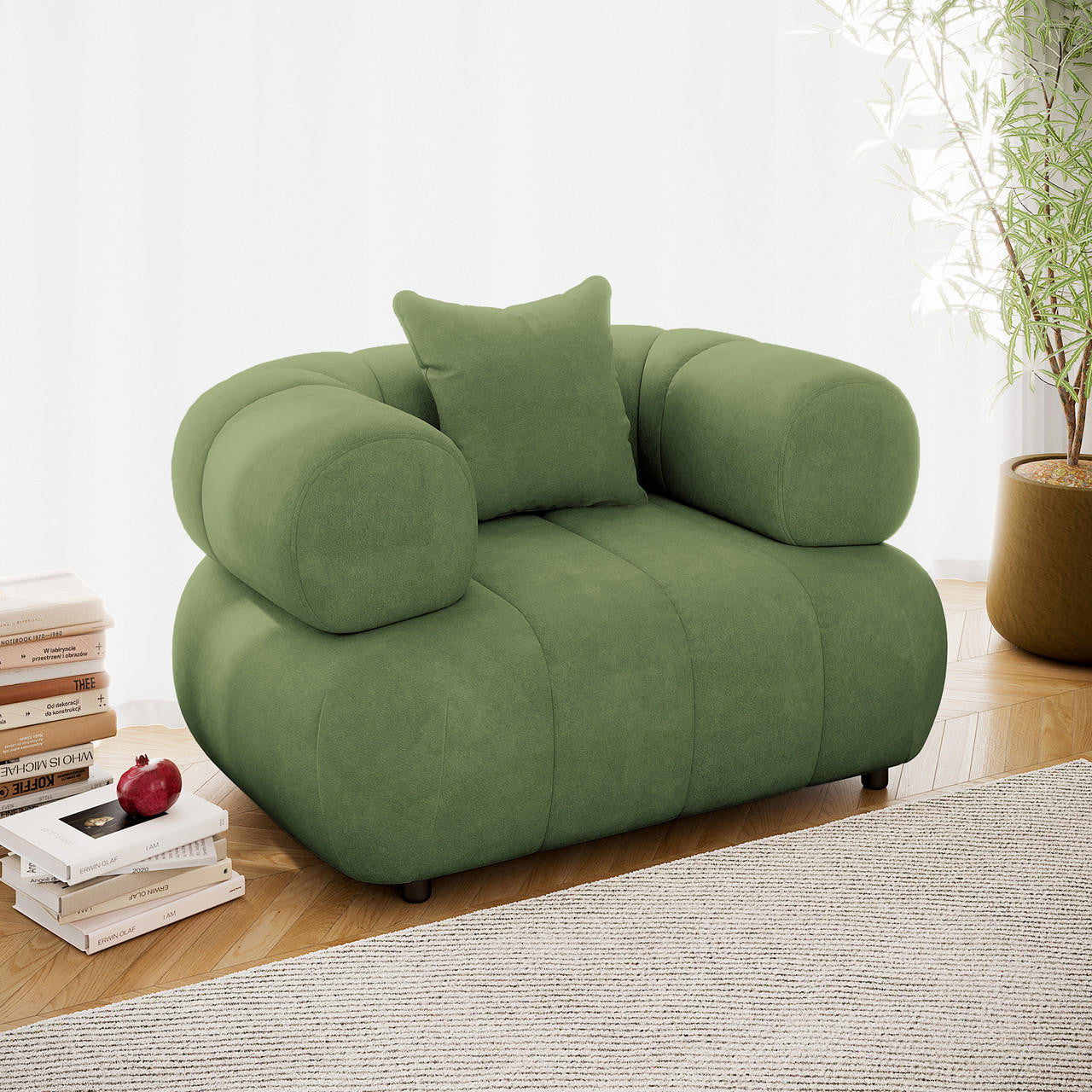Samira Single Seater Velvet Sofa in Prasinous Green, featuring soft green upholstery, thick armrests, and a matching pillow, set on a herringbone floor with books and a potted plant nearby.