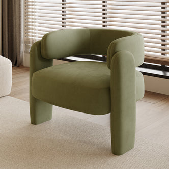 Seto Velvet Curved Occasional Accent Chair - Sage, featuring a curved backrest and thick cushioning, sits on a light rug in a bright room with wood-tone flooring and a large window.
