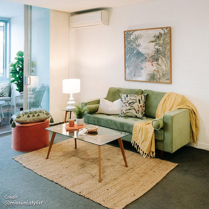 Sollia 3-Seater Velvet Sofa in jade green, featuring plush upholstery with two bolster pillows and a yellow blanket, is complemented by a coffee table, enhancing the elegant living room setting.