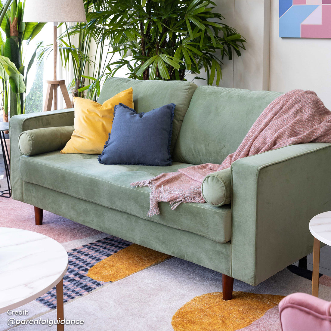 Sollia 3-Seater Velvet Sofa in jade green with plush velvet upholstery, matching round bolster pillows, and stylish wooden feet, showcased in a cozy setting with a green couch and pillows.