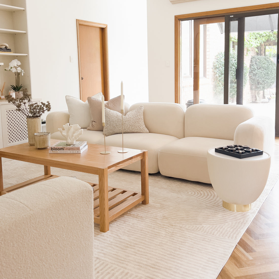 Soraya 3 Seater Modular Velvet Sofa Set in Cream White, featuring plush velvet upholstery, low-rise design, and modular configuration in a sophisticated living room setting with coffee table and book.