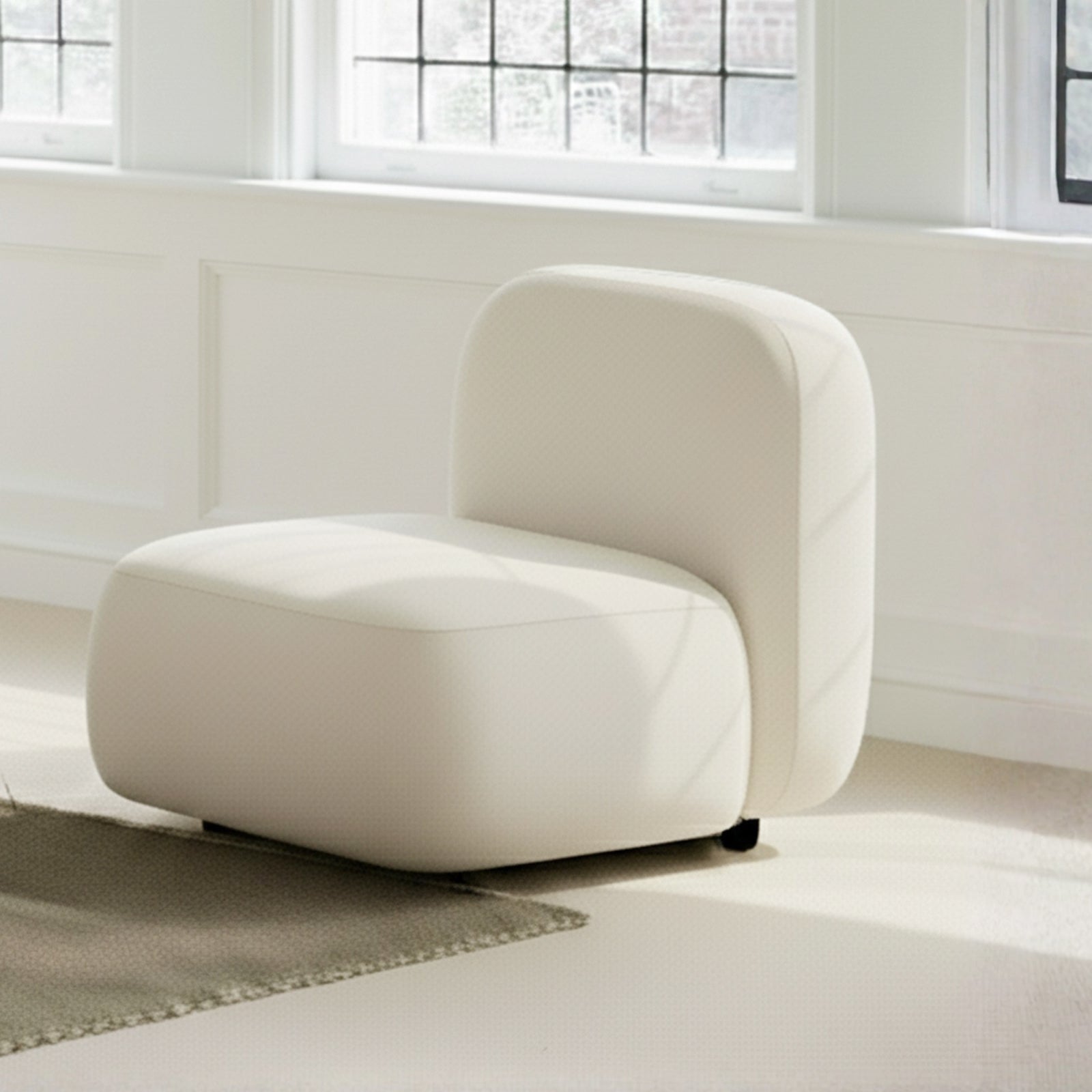 Soraya Velvet Sectional Single Sofa in Cream White, featuring a rounded silhouette, low square seat, and backrest with off-white velvet upholstery, set on small legs against a light-filled interior.