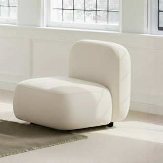 Soraya Velvet Sectional Single Sofa in Cream White, featuring a rounded silhouette, low square seat, and backrest with off-white velvet upholstery, set on small legs against a light-filled interior.