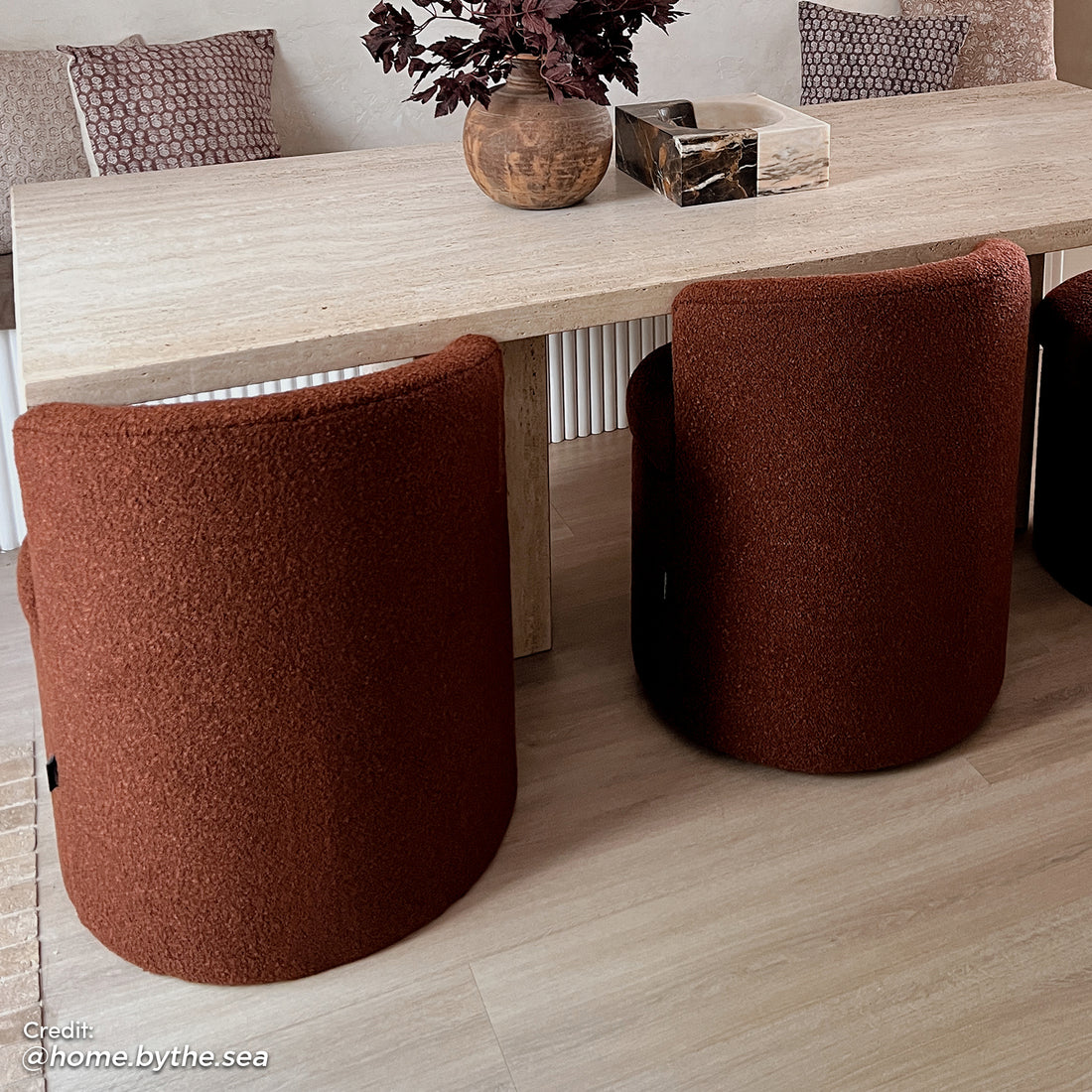 Sorra Boucle Swivel Storage Accent Chair in Rust Brown features a rich rust-bouclé fabric, barrel shape, and hidden storage. Positioned in a modern dining corner with light wood-look flooring.