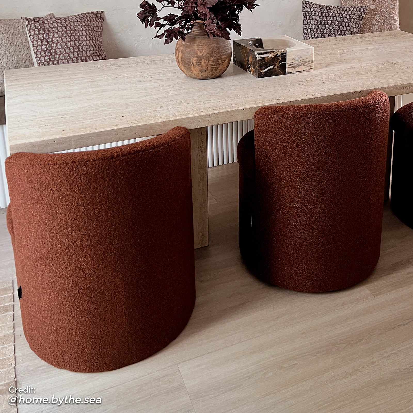 Sorra Boucle Swivel Storage Accent Chair in Rust Brown features a rich rust-bouclé fabric, barrel shape, and hidden storage. Positioned in a modern dining corner with light wood-look flooring.