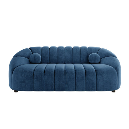 Trina 3 Seater Tufted Velvet Sofa in Blue, featuring a deep navy-blue velvet finish, rounded frame, vertical channel-tufting, and includes two matching cylindrical bolster pillows for a modern, elegant look.