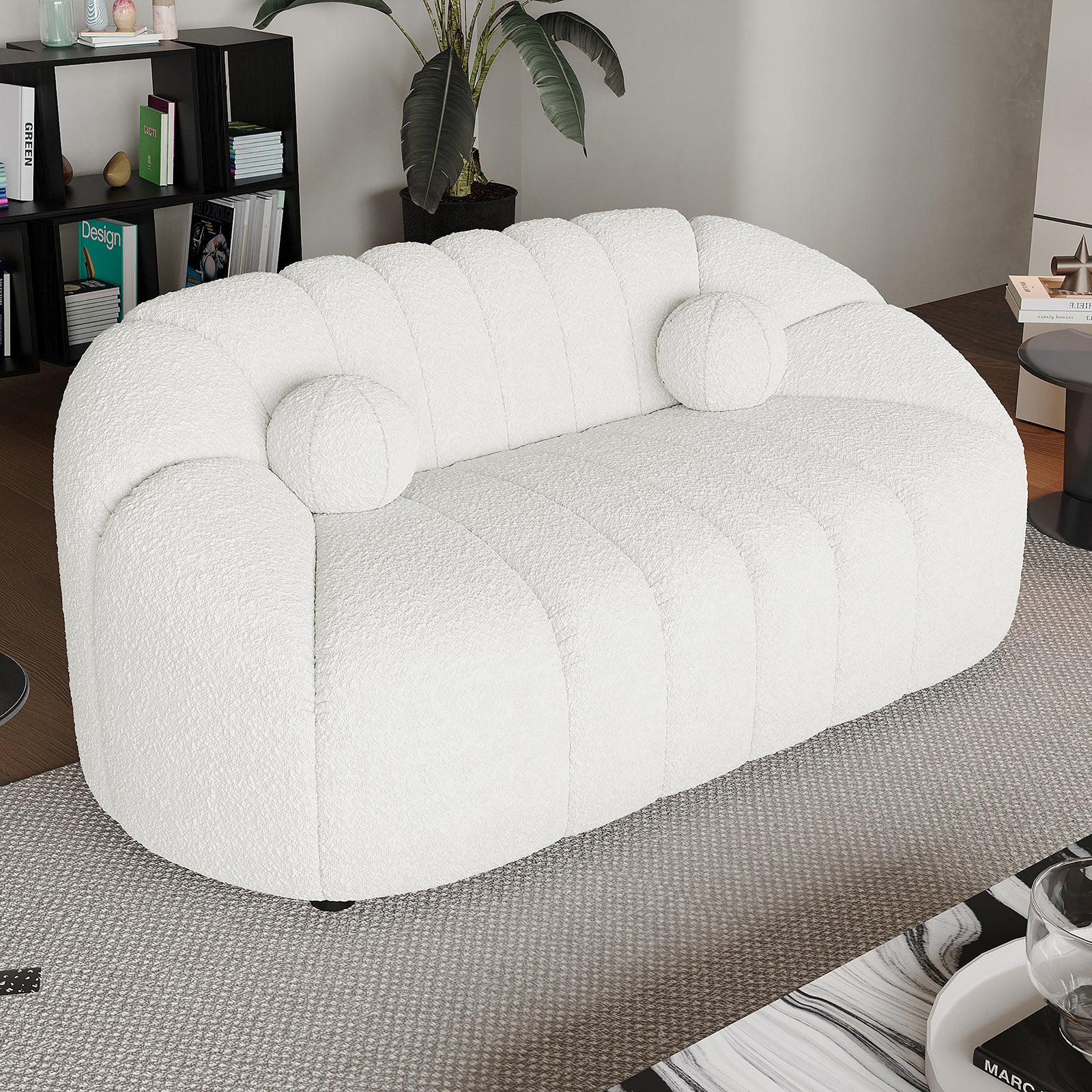 Trina 2 Seater Boucle Sofa with Pillows in Cream White, featuring a channel-stitched design, round bolsters, and set in a modern living room with a rug and plants.