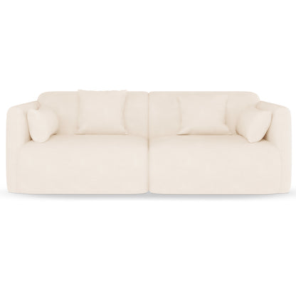 Vestalia 3 Seater Velvet Sofa in Cream White features a modern, low-profile design with two adjoining modules, upholstered in soft fabric, and includes four matching throw pillows for added elegance.