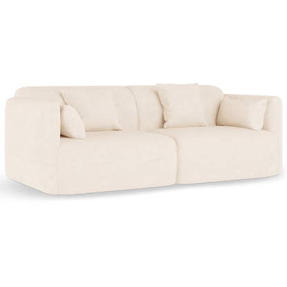 Vestalia 3 Seater Velvet Sofa in Cream White features a modern, low-profile design with two rounded-corner modules, deep seats, plush back cushions, and four matching throw pillows, exuding a sleek, contemporary look.