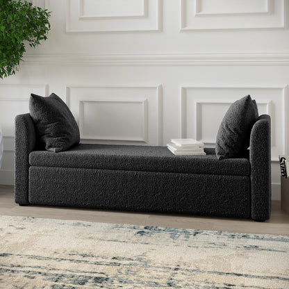 Zamira Large Boucle Storage Ottoman Bench in Charcoal, featuring a modern design with low armrests and matching back cushions, set against a white wall, with books placed on the seat.