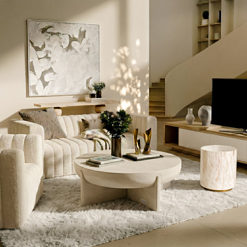 Modern dining room featuring a round light-toned dining table with six brown upholstered chairs, a sculptural pendant light overhead, a neutral patterned rug, soft sheer curtains, indoor plants, and abstract wall art, with natural light coming through large glass doors.