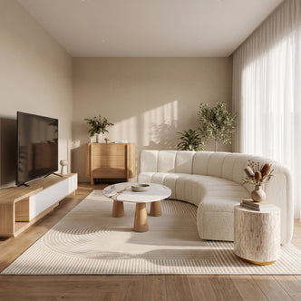 Curved white bouclé modular sofa on a neutral patterned rug with a round marble coffee table.
