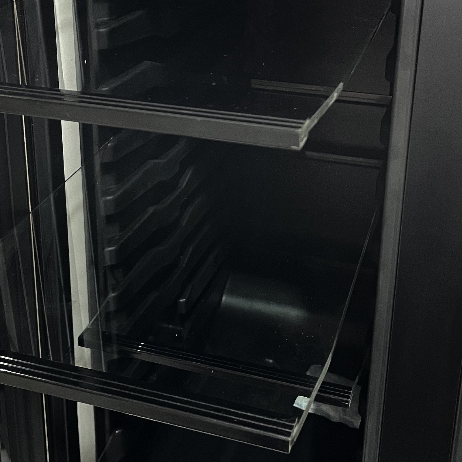 Interior view of the H140D 140L Dual Zone Wine Fridge with Chiller in Black, showcasing adjustable side rails and clear glass shelves for versatile beverage storage.