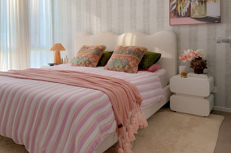 Luxo Living boucle bed frame style and modern curved bedside table with pink and orange stylish bed linen in a trendy bedroom