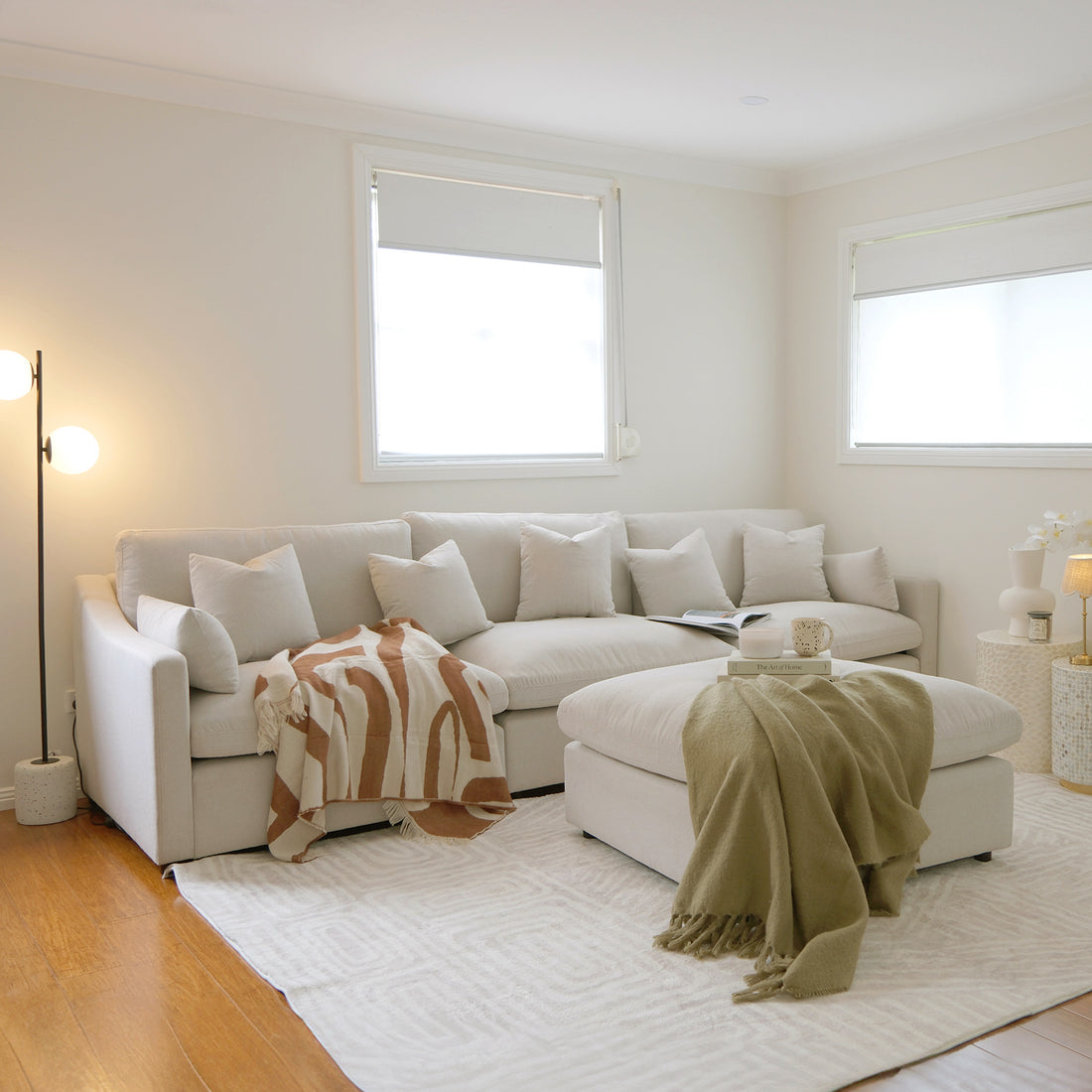 Light neutral sectional sofa with ottoman in a bright living room