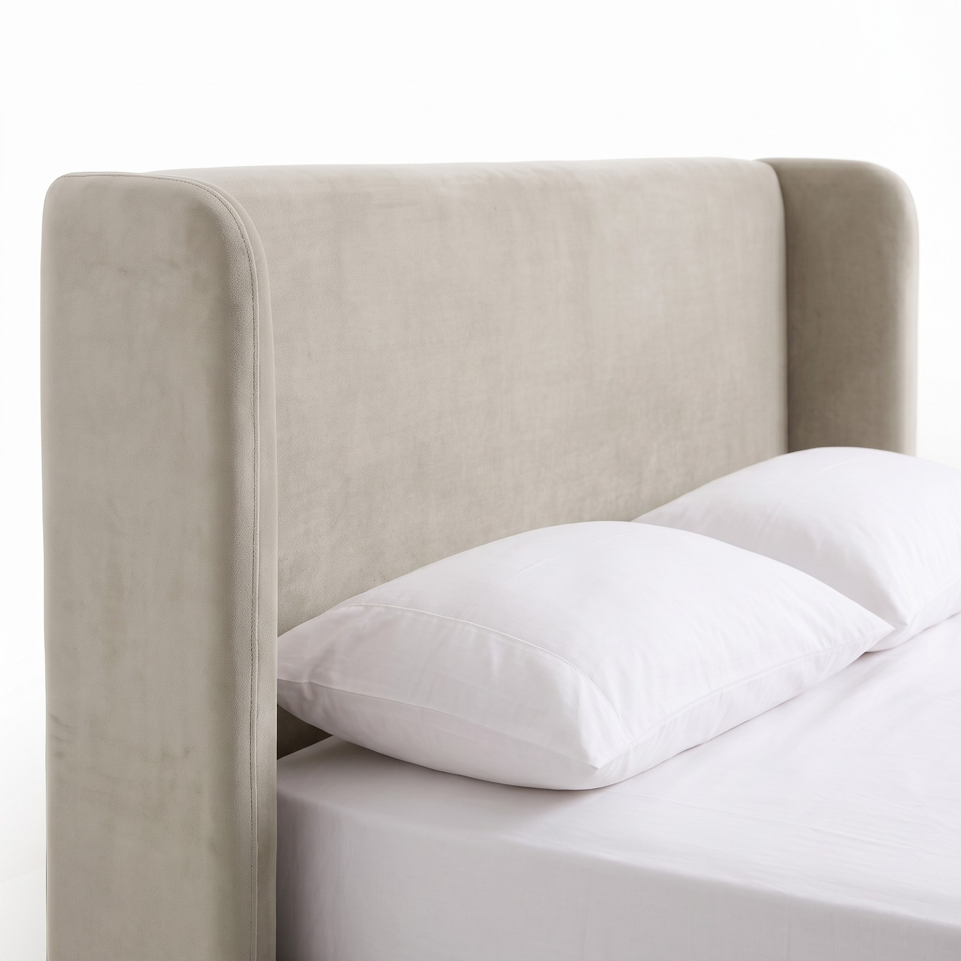 Partial view of an upholstered bed with headboard and pillows on a white background