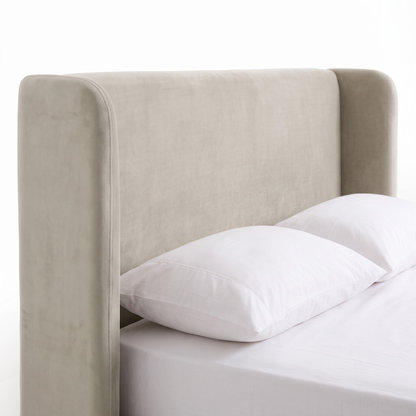 Partial view of an upholstered bed with headboard and pillows on a white background