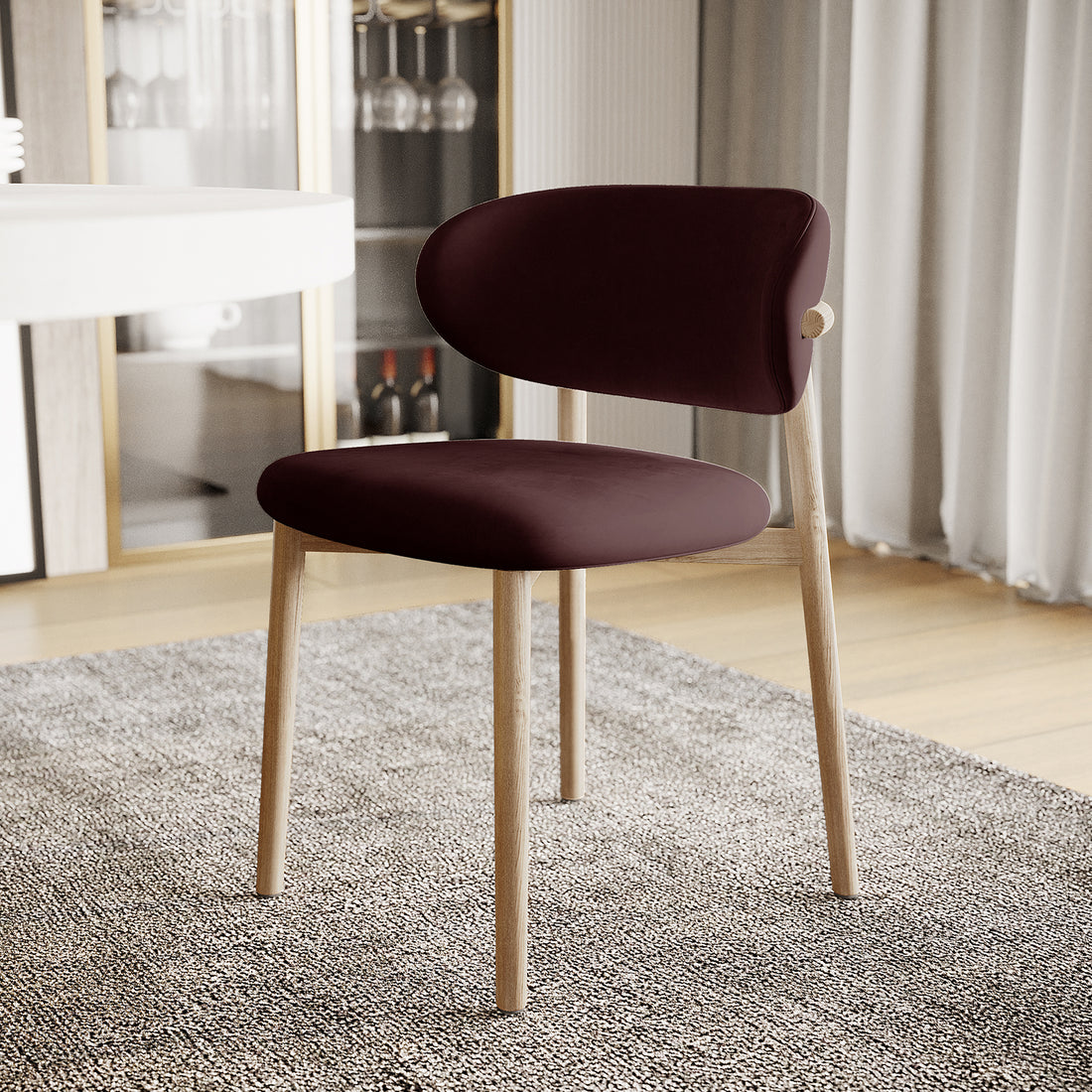 Audrey Fabric Dining Chair Set of 2 in Dark Plum, featuring a burgundy upholstered seat and backrest with light-wood legs, is showcased on a textured rug in a softly lit dining space.
