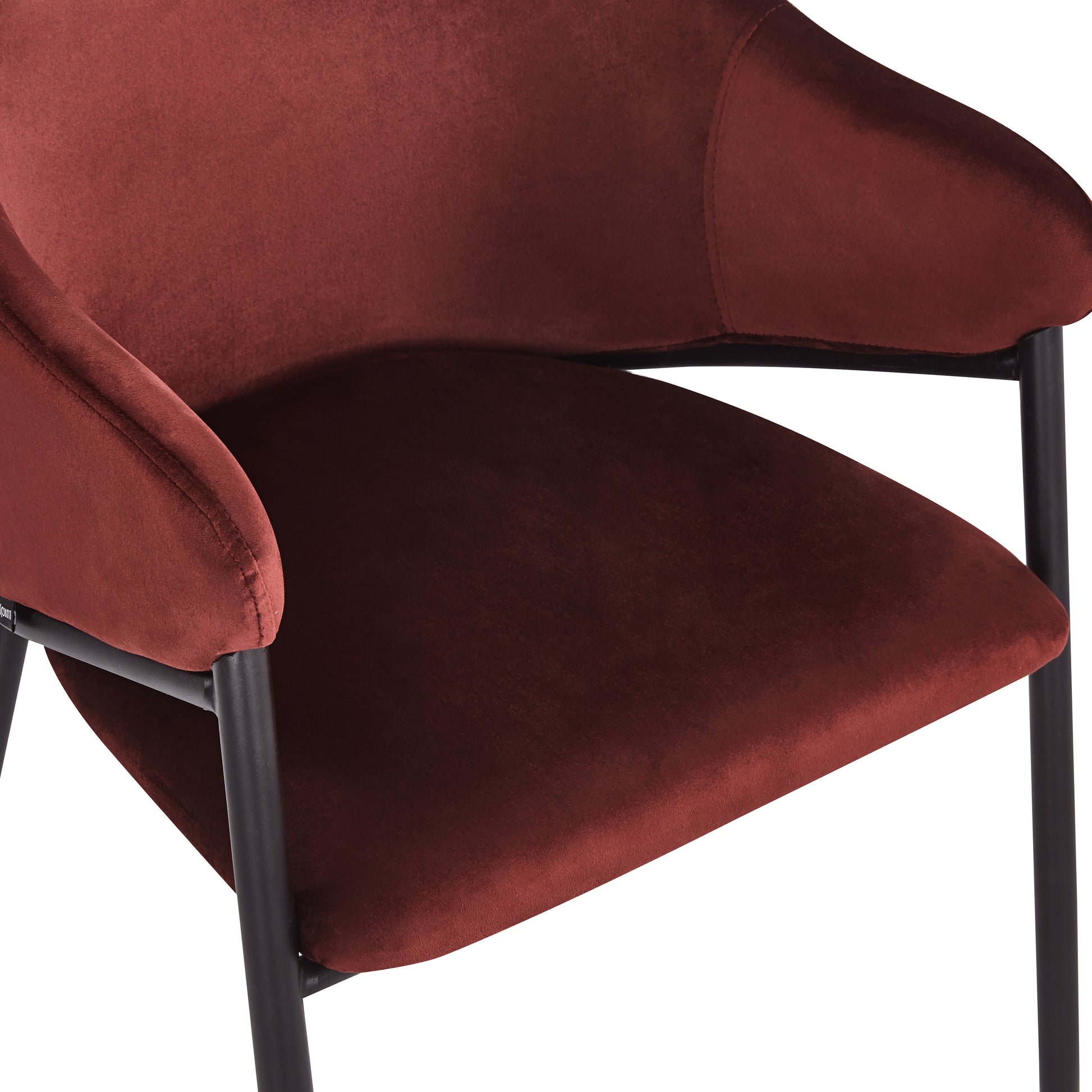 Close-up detail of burgundy velvet chair’s seat and armrest on white background