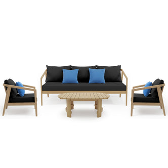Delva 4 Seater Hardwood Acacia Outdoor Sofa Set in Black features a three-seat sofa, two matching armchairs with blue throw pillows, and a slatted wood coffee table, creating a modern lounge arrangement.