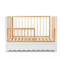 Modern white and natural wood baby crib with scalloped base on white background