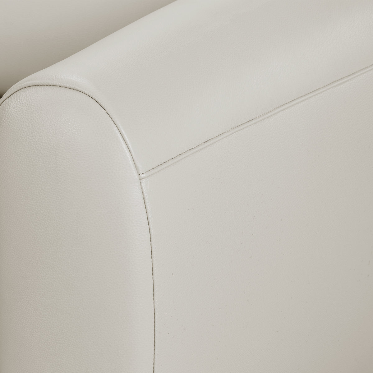 Close-up of a light-colored upholstered sofa armrest with stitching