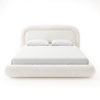 Front view of a complete cream upholstered bed with rounded headboard, mattress, pillows, and padded footboard on a white background