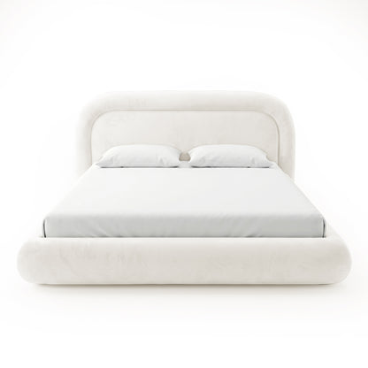Front view of a complete cream upholstered bed with rounded headboard, mattress, pillows, and padded footboard on a white background
