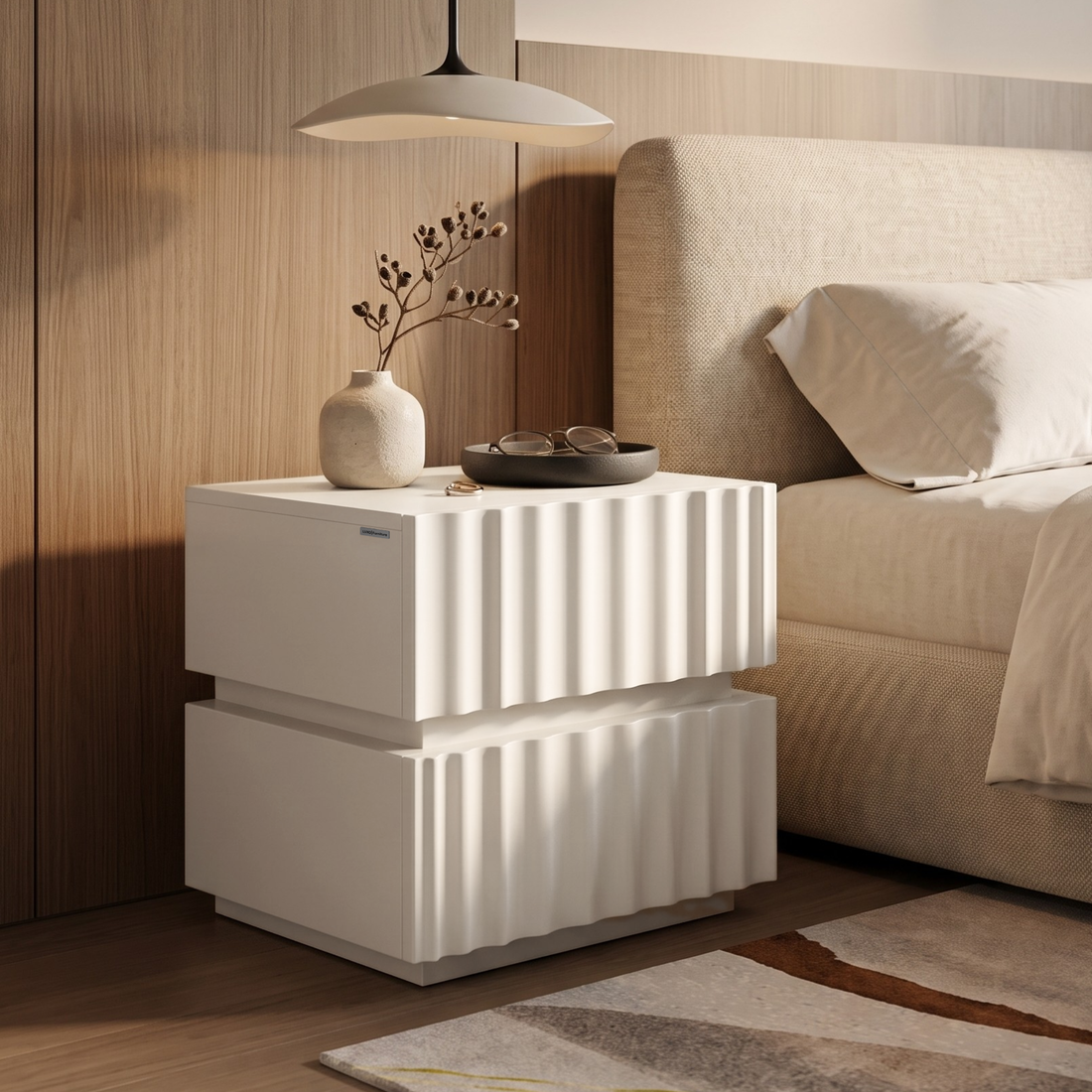 White textured nightstand styled beside a bed in a bedroom.