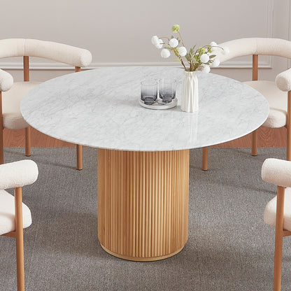 Gracie 120cm Round Marble Dining Table features a white marble top and cylindrical wooden base, surrounded by cream boucle chairs with tubular armrests, creating a minimalist dining setup with understated elegance.