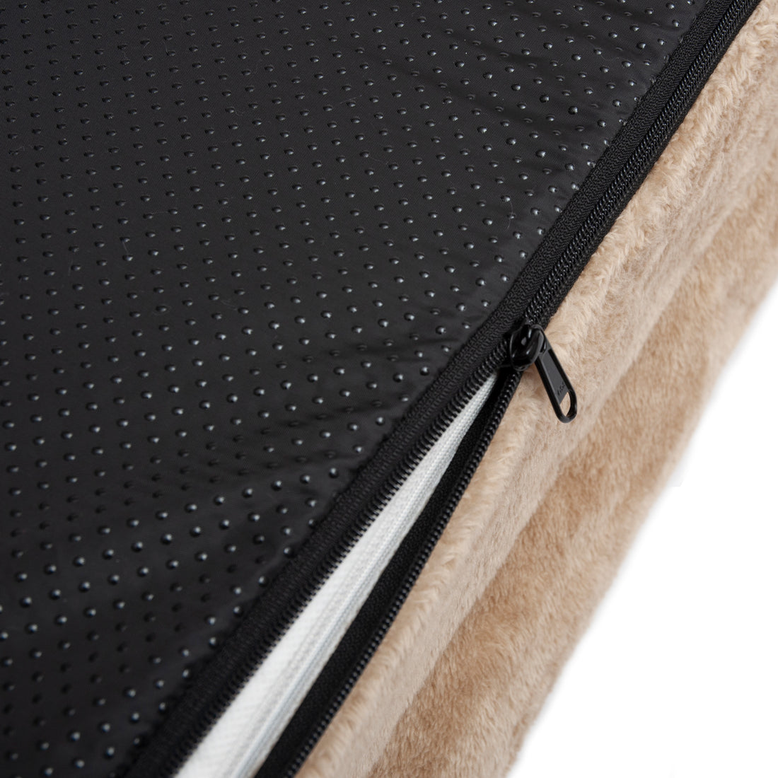 Close-up of beige and black fabric with zipper revealing inner padding