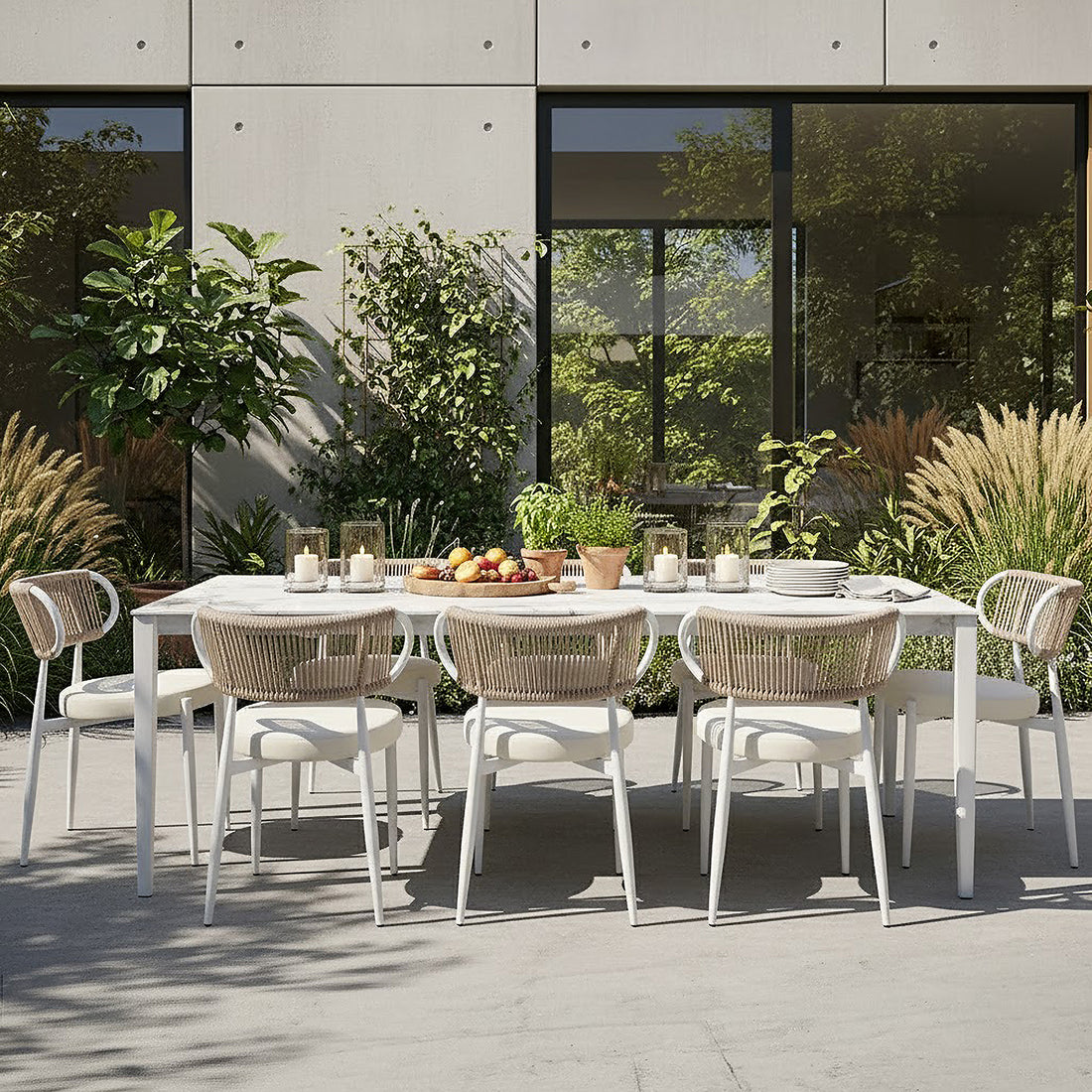 Cabria 9 Piece Sintered Stone Outdoor Dining Set with a sleek white table and eight chairs featuring woven rope backs, set on a contemporary patio with lush greenery and minimalist décor.