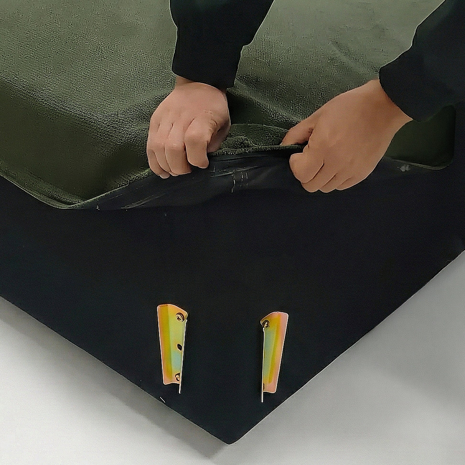 Hands unzipping green fabric cover on sofa base corner